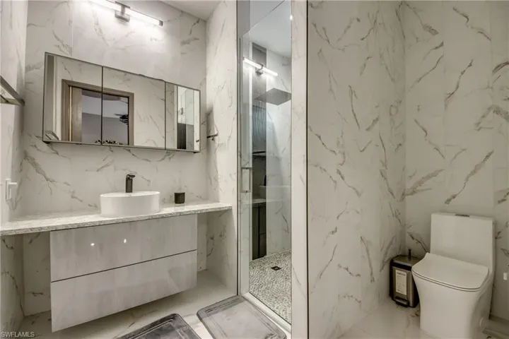 Full bathroom with stone wall, vanity, marble tiled floors, tile walls, and a marble finish shower
