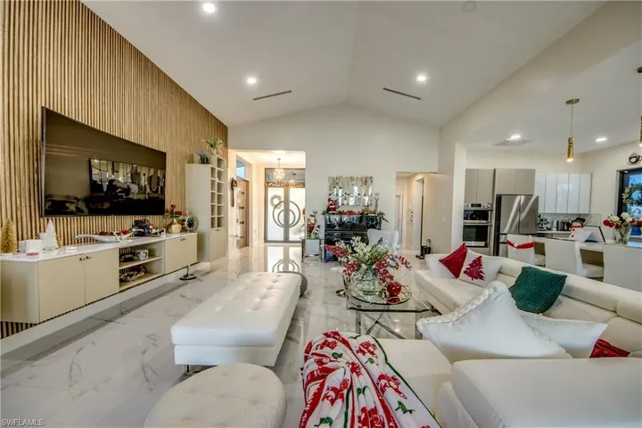 Living area featuring lofted ceiling, light marble finish floors, and wooden walls