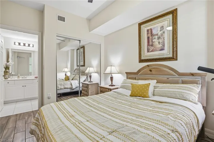 Bedroom featuring wood finish floors, a closet, ceiling fan, and ensuite bath