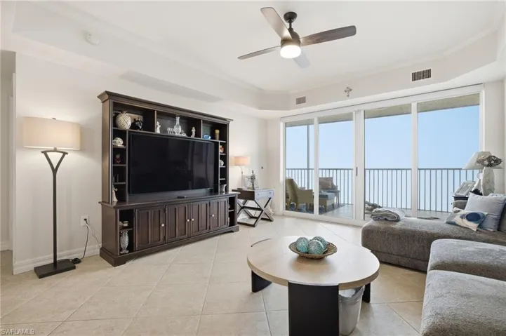 Living room featuring light tile patterned flooring, crown molding, and a ceiling fan