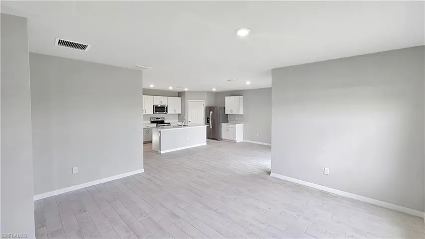 Unfurnished living room featuring sink and light wood-type flooring