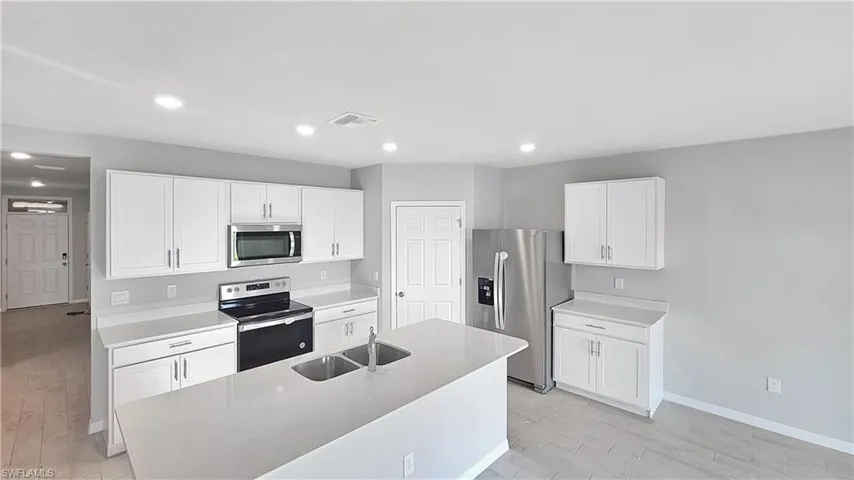 Kitchen featuring appliances with stainless steel finishes, light wood-type flooring, and a center island with sink