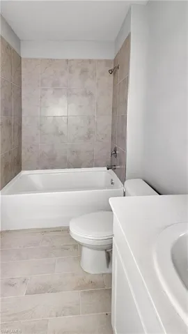 Full bathroom featuring tile flooring, tiled shower / bath combo, vanity, and toilet