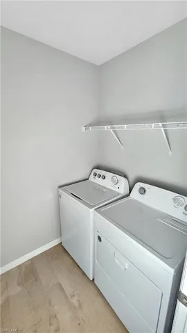 Laundry room featuring independent washer and dryer and light hardwood / wood-style flooring