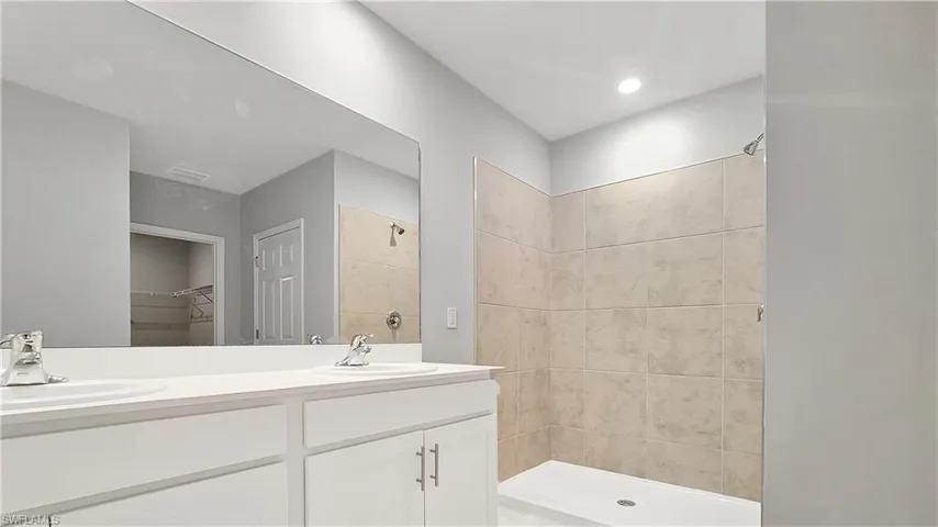 Bathroom featuring dual vanity and a tile shower