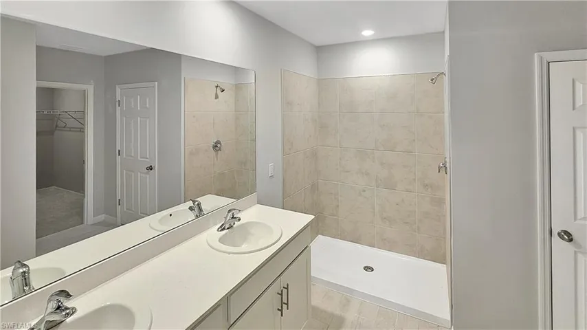 Bathroom featuring dual bowl vanity, a tile shower, and hardwood / wood-style flooring