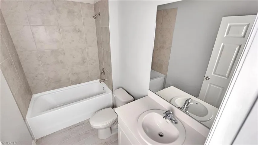 Full bathroom with tile flooring, toilet, washer / dryer, tiled shower / bath combo, and oversized vanity