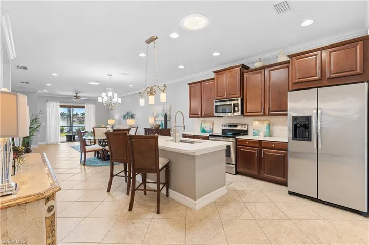 Kitchen featuring stainless steel appliances, hanging light fixtures, ornamental molding, and sink
