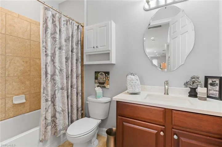 Full bathroom with vanity, shower / bath combination with curtain, and toilet