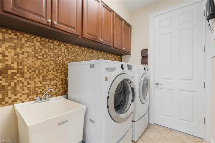 Laundry area featuring cabinets, independent washer and dryer, light tile patterned floors, and sink
