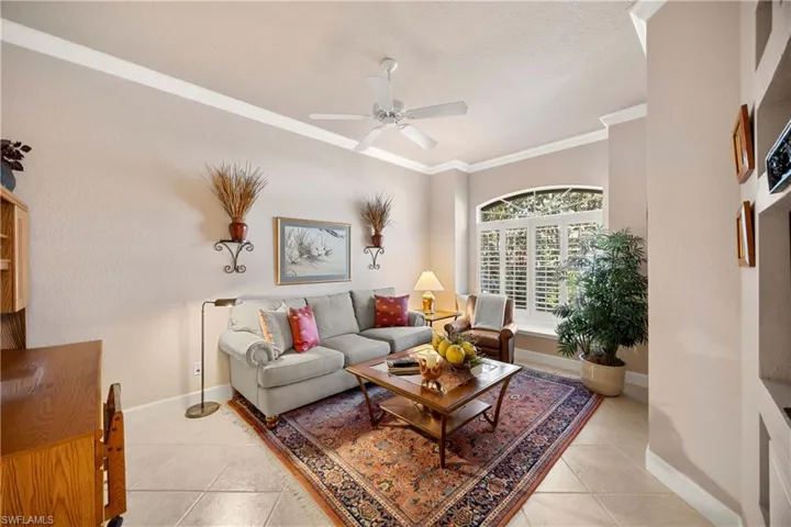 Bedroom used as a den featuring ornamental molding, light tile patterned floors, and a ceiling fan