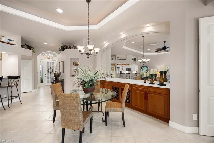 Dining space featuring a tray ceiling, a chandelier, light tile patterned floors, recessed lighting, and ornamental molding