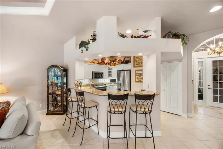 Kitchen with a kitchen breakfast bar, a peninsula, glass insert cabinets, stainless steel appliances, and light stone counters