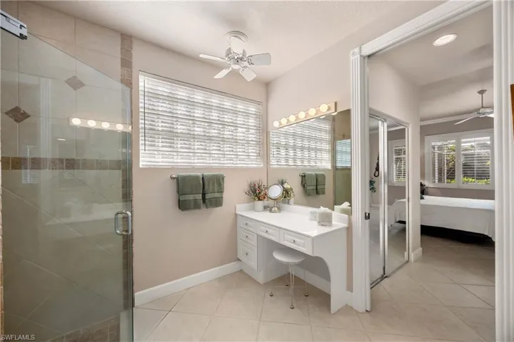 Primary bathroom with ceiling fan, connected bathroom, light tile patterned flooring, and a textured ceiling