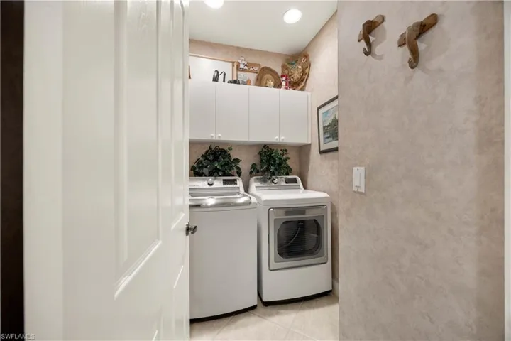 Laundry area featuring light tile patterned floors, cabinet space, and independent washer and dryer