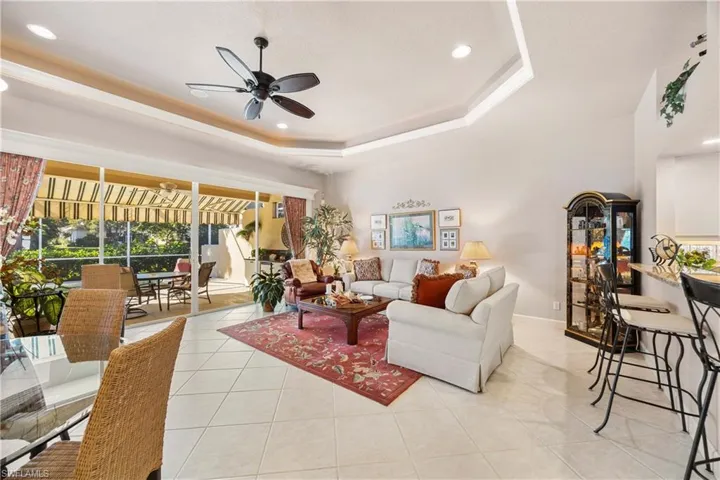 Living area featuring recessed lighting, a tray ceiling, light tile patterned floors, ceiling fan, and a sunroom