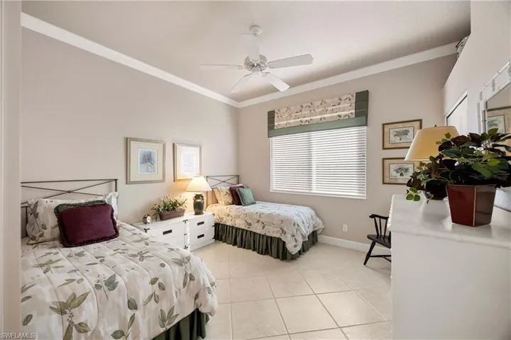 Guest Bedroom with ornamental molding, light tile patterned floors, and a ceiling fan