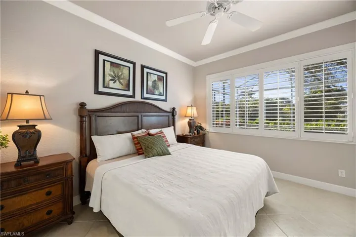 Bedroom with crown molding, light tile patterned floors, and a ceiling fan