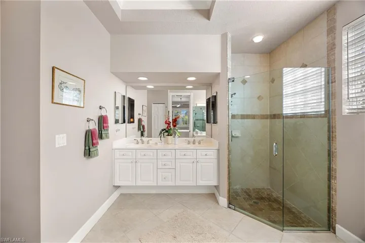 Primary Bathroom featuring double vanity, a stall shower, light tile patterned flooring, recessed lighting, and a textured ceiling