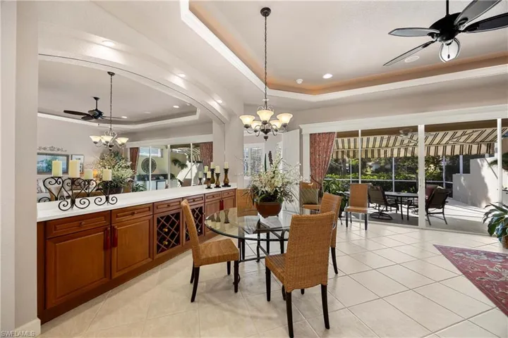 Dining room with a ceiling fan, a raised ceiling, a chandelier, and recessed lighting