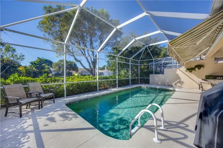 Outdoor pool with a patio area, a sunroom, glass enclosure, and a grill