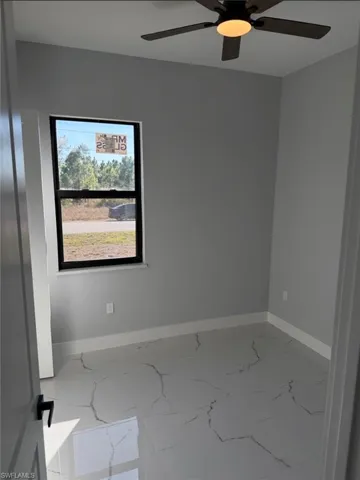 Unfurnished room featuring a ceiling fan and light marble finish floors