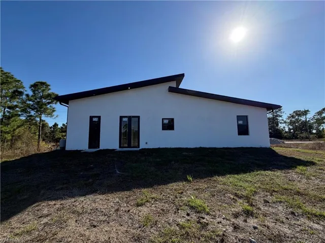 Rear view of house with stucco siding and a yard
