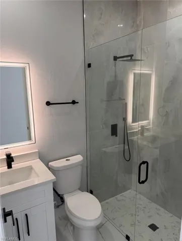 Full bath featuring vanity, a marble finish shower, and a textured wall