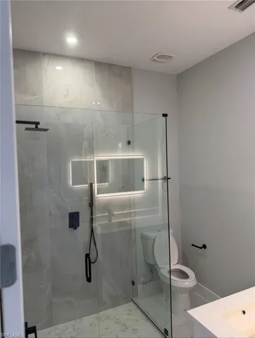 Full bath featuring a marble finish shower, vanity, and marble look tiles