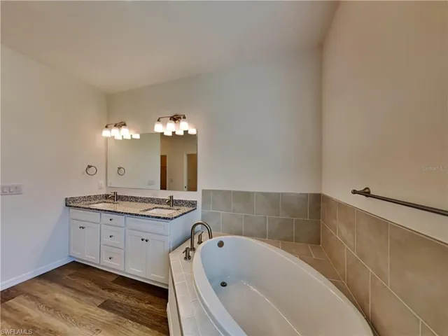Picture of a previously completed home Full bathroom featuring a garden tub, double vanity, and wood finished floors