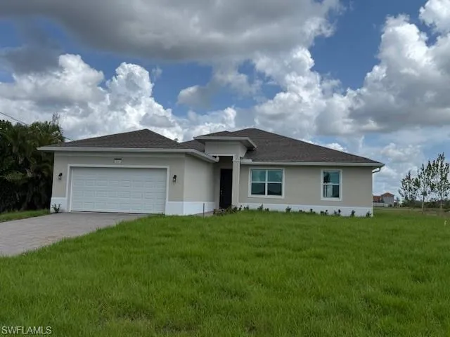 View of front of property featuring stucco siding, decorative driveway, a front yard, and an attached garage