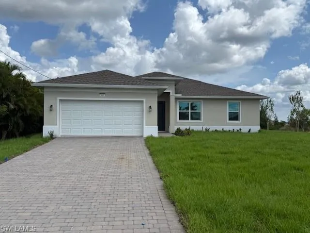 View of front of home with decorative driveway, stucco siding, an attached garage, and a front yard