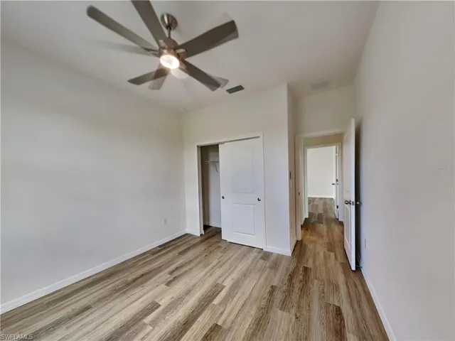 Picture of a previously completed home Unfurnished bedroom featuring wood finished floors, a closet, baseboards, and a ceiling fan