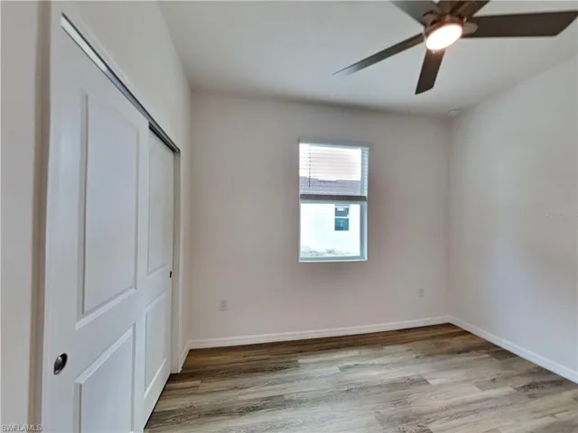 Picture of a previously completed home Unfurnished bedroom featuring wood finished floors, a closet, ceiling fan, and baseboards