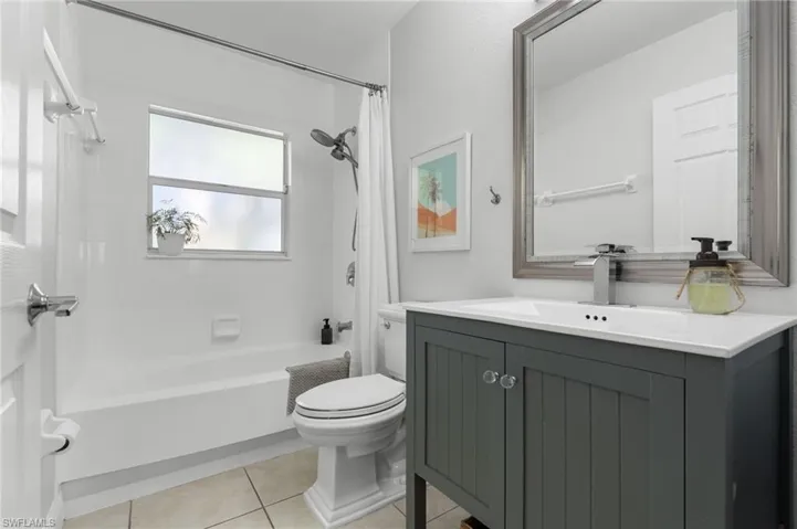 Modern bathroom featuring a dark grey vanity with a white countertop and integrated sink, chrome faucet, and a large framed mirror