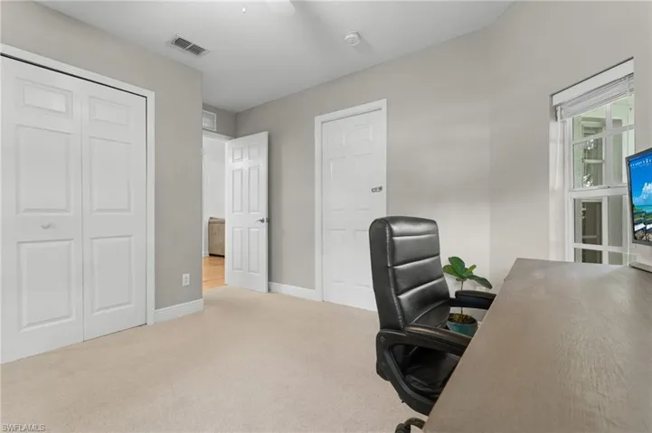Carpeted room featuring light gray walls, white baseboards, and a white ceiling fan