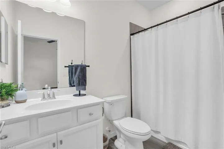 Bathroom featuring curtained shower, toilet, and vanity