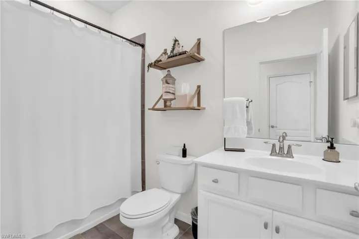Full bathroom with wood-type flooring, toilet, shower / tub combo, and vanity