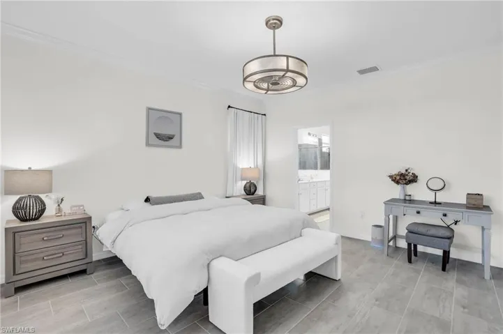 Bedroom featuring ensuite bathroom, an inviting chandelier, and ornamental molding