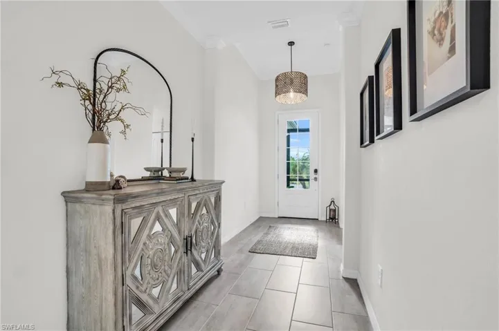 Entryway featuring light tile patterned floors, a notable chandelier, and ornamental molding