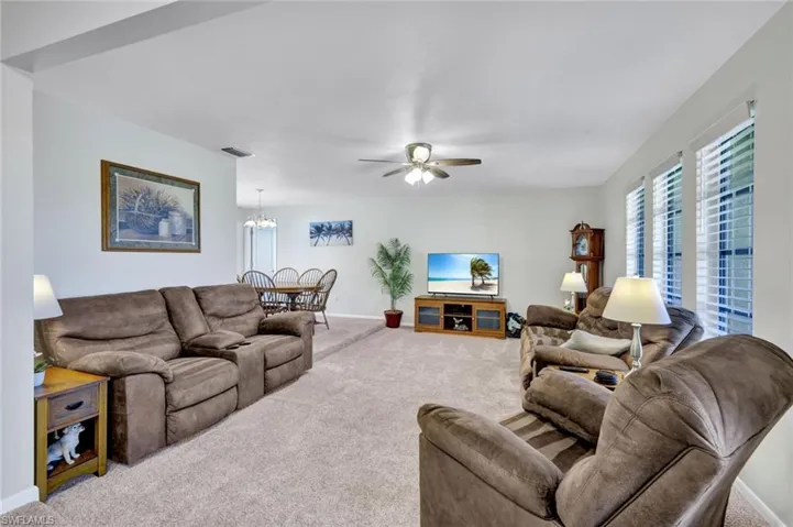 Carpeted living room featuring ceiling fan and a chandelier
