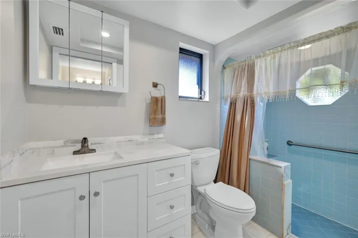 Bathroom featuring vanity, tiled shower, and light tile patterned flooring