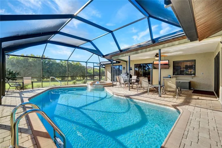 View of pool featuring a patio area, glass enclosure, a sunroom, and a pool with connected hot tub