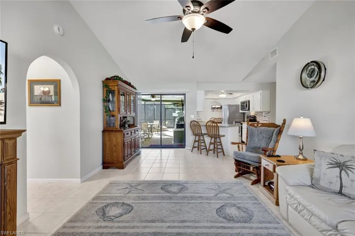 Living room with light tile patterned floors, ceiling fan, and high vaulted ceiling