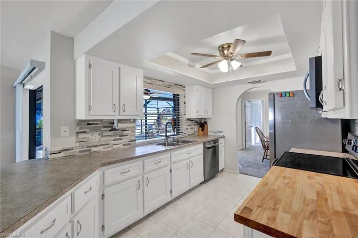 Kitchen featuring arched walkways, white cabinetry, tasteful backsplash, and ornamental molding