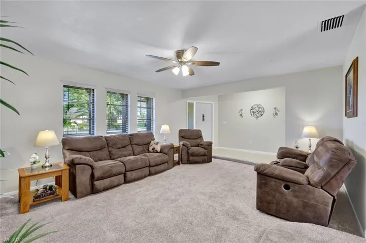 Carpeted living area featuring a ceiling fan and baseboards
