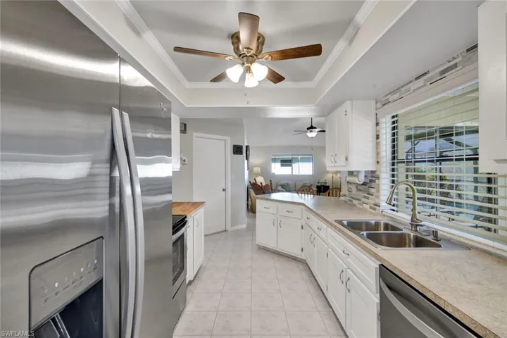 Kitchen featuring appliances with stainless steel finishes, tasteful backsplash, white cabinets, a ceiling fan, and a peninsula