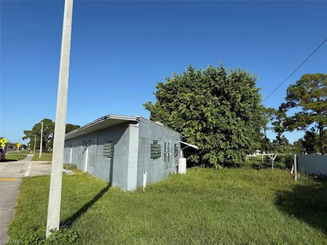 View of side of home featuring concrete block siding and a yard