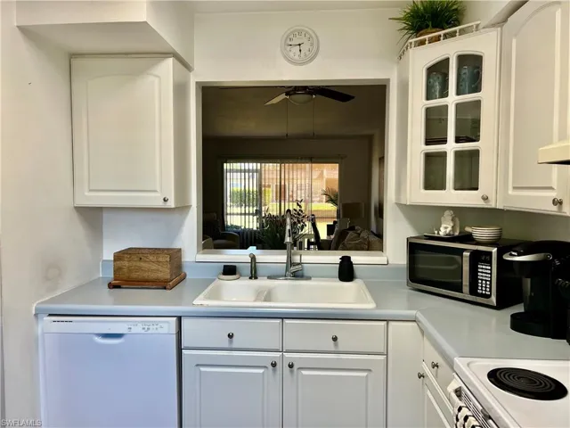 Kitchen featuring white appliances, white cabinets, and light countertops
