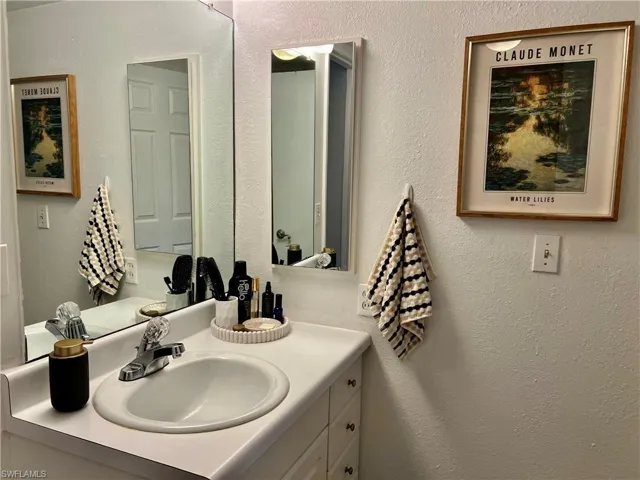 Bathroom with a textured wall and vanity